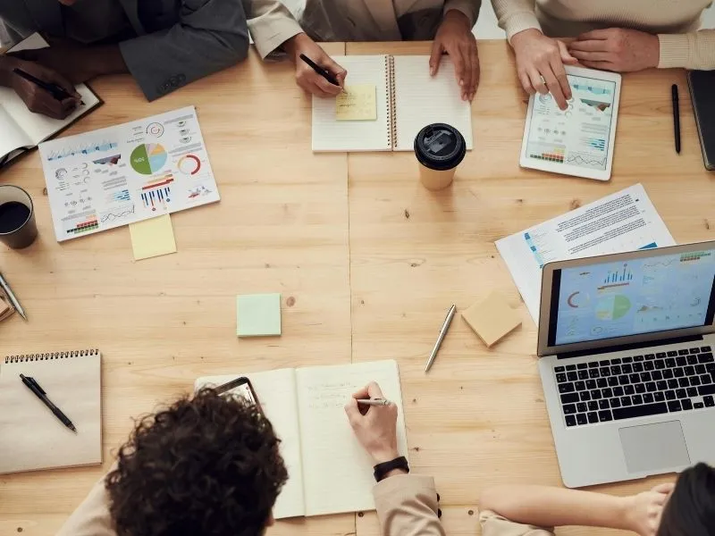 group of professionals sitting at meeting looking at graphs and statistics