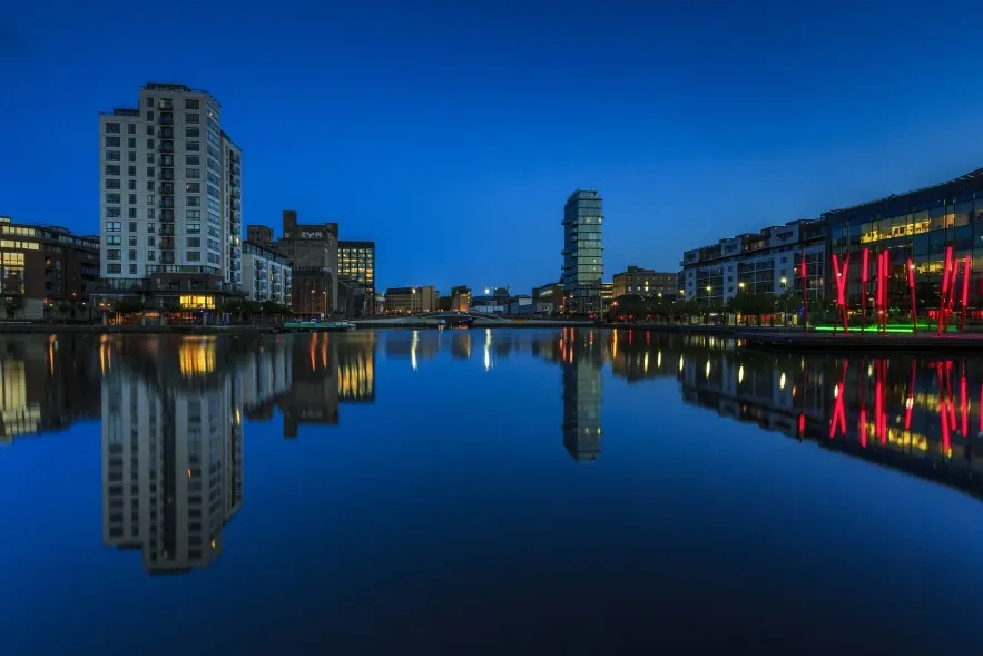 Modern city at dusk with buildings and skyscrapers next to a river, symbolising the Corporation Tax.