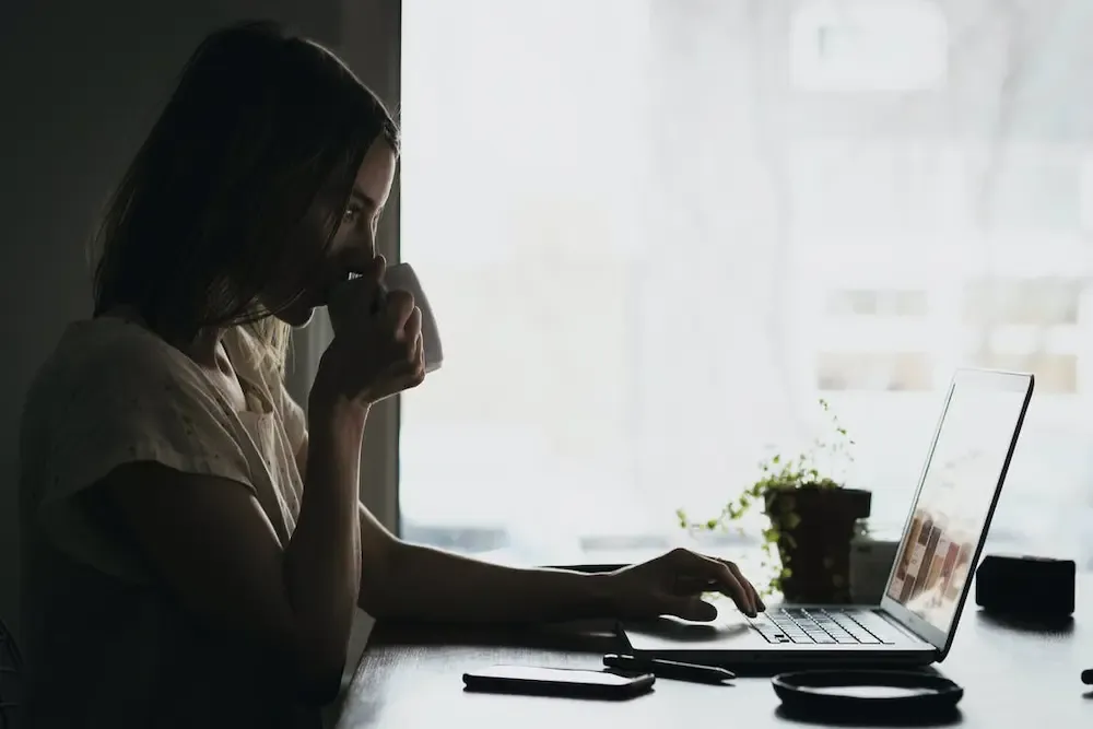 Professional woman at a desk with a laptop and coffee, efficiently managing CRO B1 Annual Return filing for Irish companies.