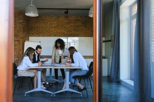 Team collaborating around a desk in an office, indicating commitment to our Nominee Company Secretary service.