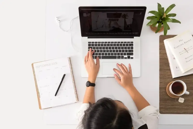 Woman at a desk with a laptop, notebook, pen and a cup of tea, illustrating her focus at understanding Company Constitution.