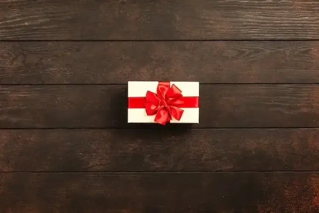 Small white gift box with a red bow on a wooden table, symbolising the Small Benefit Exemption in Ireland.